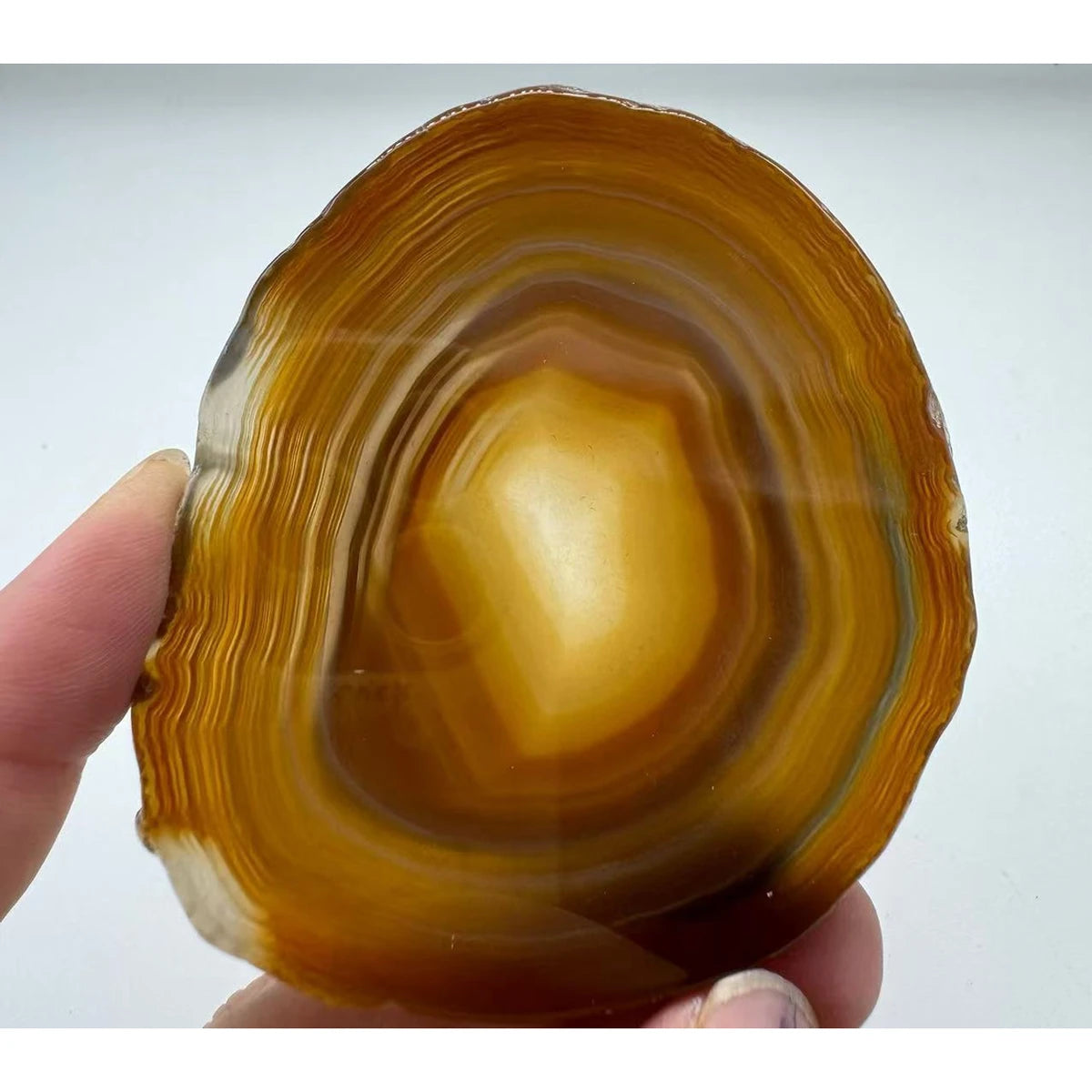 Natural agate slice coaster, 8-10 cm, held in a hand for scale