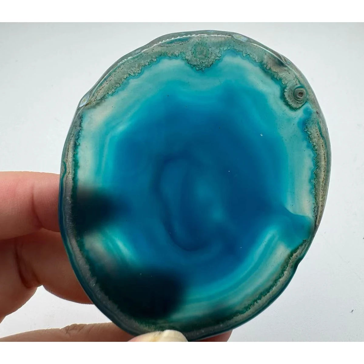 Natural agate slice coaster, 8-10 cm, held in a hand for scale
